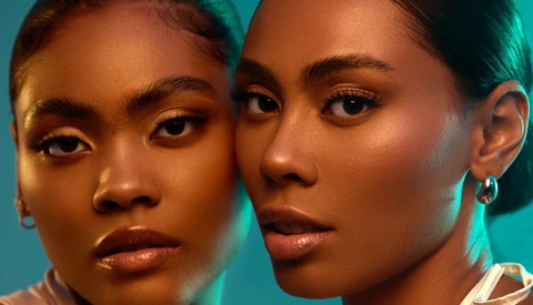 Two women with warm-toned skin positioned close together against a turquoise background.