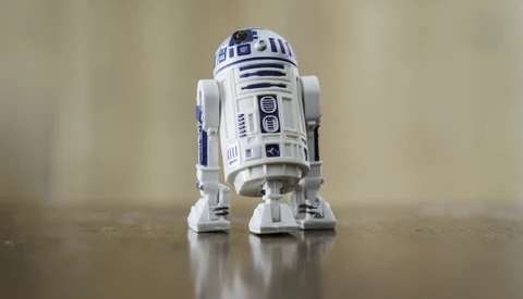 R2-D2 droid action figure photographed on a reflective surface against a soft neutral background.