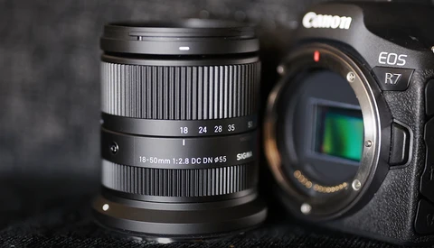 Canon EOS R7 camera body with Canon RF 18-50mm f/2.8 DC DN Contemporary lens on dark surface.
