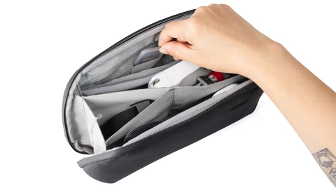 Hand opening a black camera bag organizer with gray interior compartments and dividers.