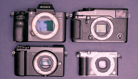 Four compact digital cameras arranged on a purple background, displaying various form factors and designs.