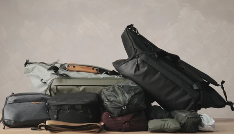 Collection of camera bags and travel gear organized in a flat lay arrangement against a neutral background.