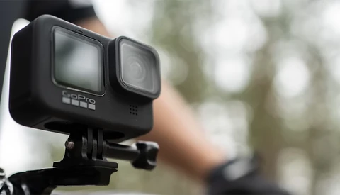 GoPro Hero 11 action camera mounted on a tripod bracket, shown in sharp focus against a blurred outdoor background.