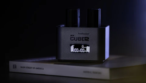 Roland Cube2 amplifier displaying digital clock on dark surface with book beside it.