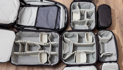 Collection of open camera equipment organizer cases with customizable padded dividers on wooden surface.