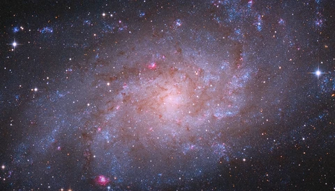Spiral galaxy with bright central core and blue and pink star-forming regions throughout its disk.