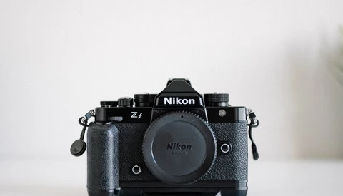 Nikon Z f mirrorless camera body with attached battery grip against white background.