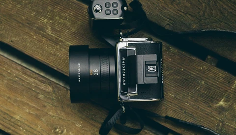 Medium format camera with standard lens and light meter on wooden surface.