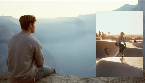 Man sitting on a cliff edge overlooking a misty mountain valley at sunrise or sunset.