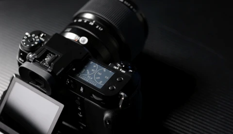 Professional DSLR camera with telephoto lens mounted on a dark textured surface.