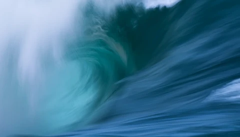 Motion-blurred wave with swirling turquoise water and dynamic flowing patterns.
