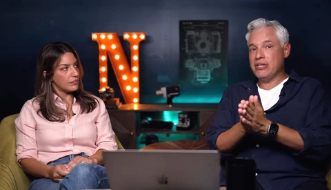 Two people seated at a table during a video interview or podcast recording setup.
