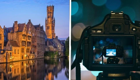 Medieval European canal city at dusk reflected in still water, with a tall bell tower illuminated against twilight sky.