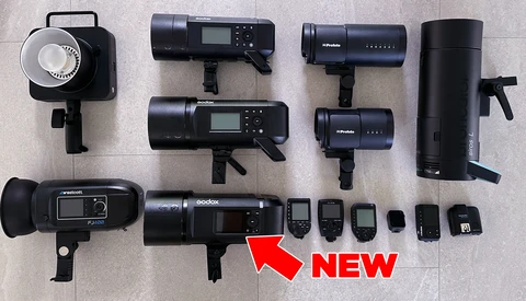 Collection of professional lighting equipment including LED panels, monolights, and wireless triggers arranged on a light surface.