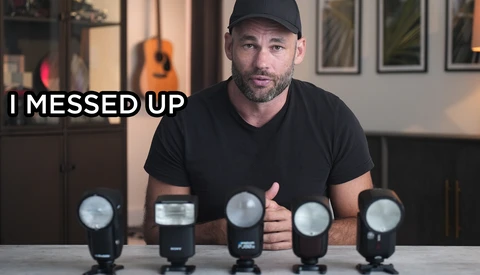 Photographer with five camera flash units arranged in a row on a table, appearing to address a mistake.
