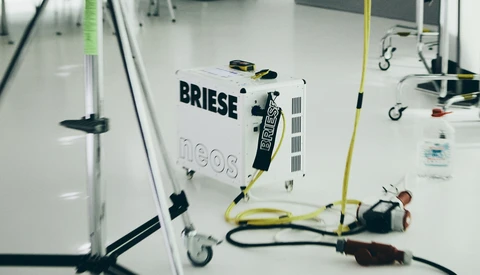 Overhead view of a Briese lighting unit on a white floor with cables and grip equipment arranged around it.