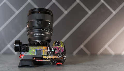 Camera lens mounted on disassembled camera body showing internal circuitry and components.