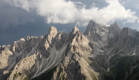 Dramatic limestone peaks of the Dolomites with layered ridges under cloudy sky.