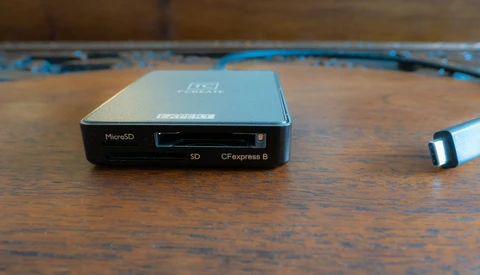 Multi-card reader with MicroSD, SD, and CFexpress B slots on a wooden surface with blue cable.
