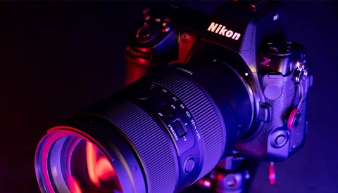 Nikon Z camera with attached lens, illuminated by red and blue studio lighting against a dark background.