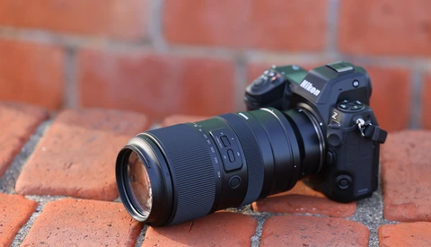 Nikon mirrorless camera with telephoto lens on red brick surface.