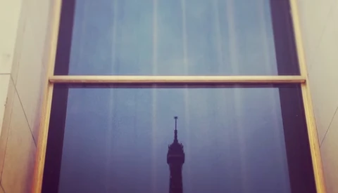 Silhouette of a tall tower visible through a window frame at dusk or dawn.