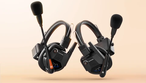 Pair of black gaming headsets with flip-up microphones positioned side by side against a beige background.