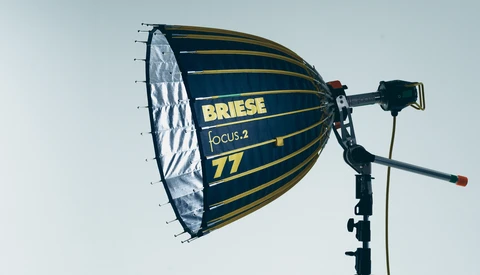 Briese Focus.2 77 parabolic softbox mounted on a light stand against a light sky backdrop.