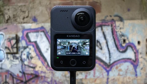 Kandao action camera mounted on stand against colorful graffiti wall backdrop.