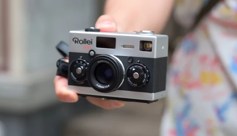 Person holding a Rollei rangefinder camera with chrome top plate and black body.