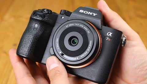 Sony a7R IV mirrorless camera held in hands with 35mm f/1.4 lens attached.