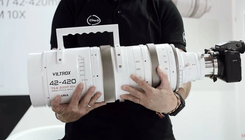Photographer holding a white Viltrox 42-420mm zoom lens with visible focus and aperture rings.