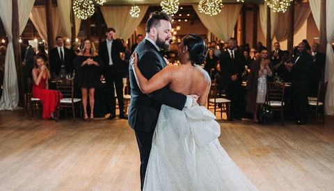 Bride and groom dancing together during their first dance at an elegant indoor wedding reception.
