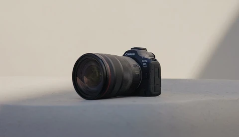 Canon EOS R5 mirrorless camera with attached telephoto lens on neutral surface.