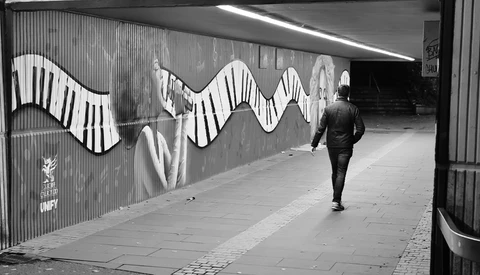 Runner jogging through an underpass with large-scale wavy piano key mural art.