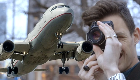 Photographer using telephoto lens with commercial aircraft in flight overhead.