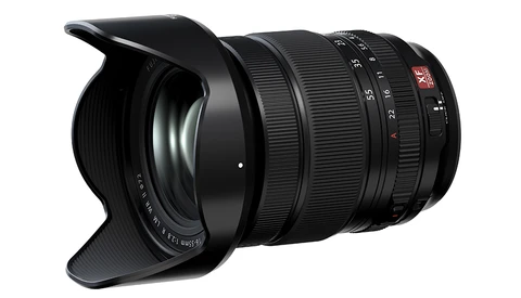 Wide-angle zoom lens with black barrel, focus ring, and attached lens hood against white background.