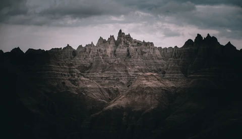 Dramatic badlands landscape with distinctive peaked formations rising against stormy sky.