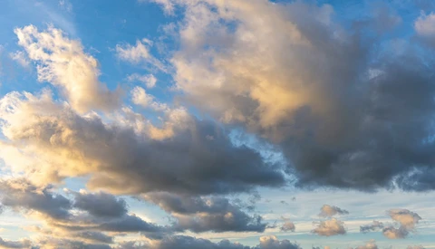 Dramatic sky at sunset with layered clouds illuminated by golden and blue light.