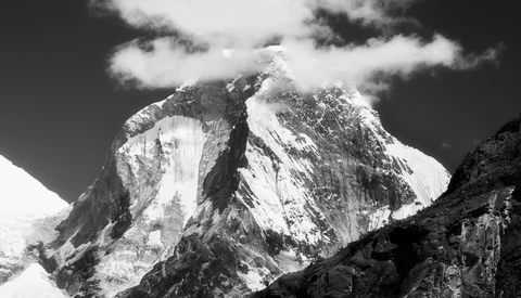 Snow-covered mountain peaks with dramatic vertical columnar formations beneath a partly cloudy sky.