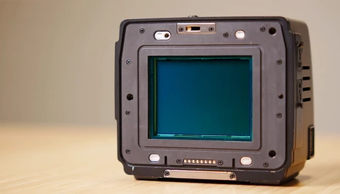 Rugged portable device with a teal-colored CRT display and metal frame, photographed against a neutral beige background.