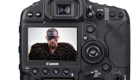 Canon EOS R5 DSLR camera displaying a portrait of a bearded man wearing dark fur on its rear LCD screen.