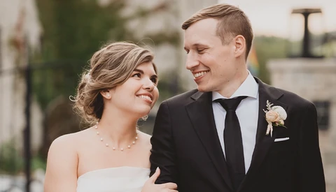 Bride and groom smiling at each other outdoors during their wedding day.
