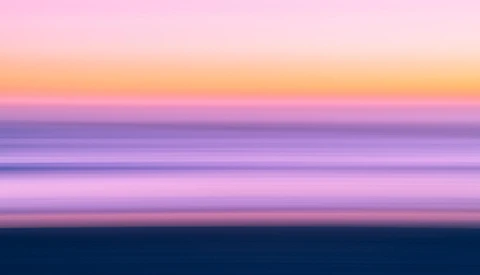 Serene seascape with layered horizontal bands of soft pink, purple, and blue tones during twilight hour.