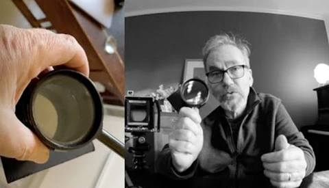 Photographer holding a circular lens filter next to a vintage film camera and light meter during a studio setup.