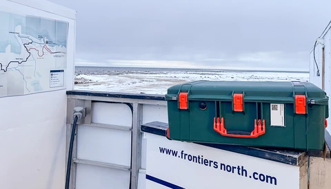 Green and red toolbox on a white van with coastal landscape visible in background.