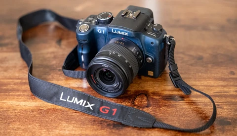 Panasonic Lumix G1 mirrorless camera with attached lens and strap on wooden surface.