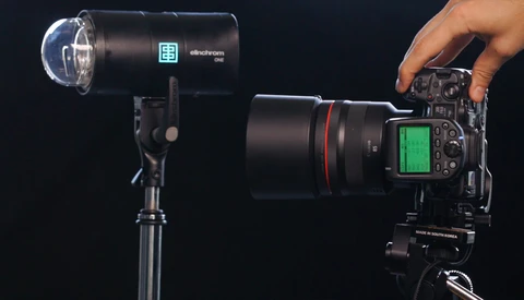 Professional monolight and DSLR camera with telephoto lens on black background.