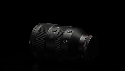 Dark telephoto lens with multiple focus distance markings against black background.