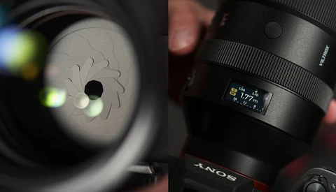 Close-up of a Sony lens showing aperture blades and focal length markings, held in natural lighting.